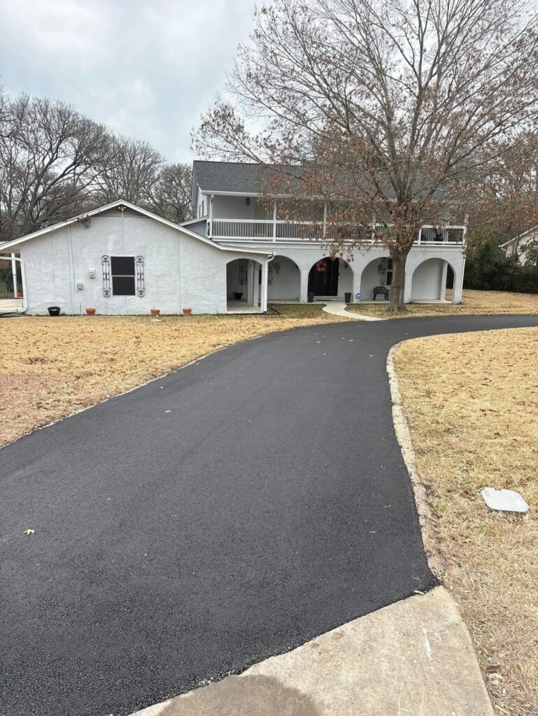 Curved asphalt driveway leading to a white house