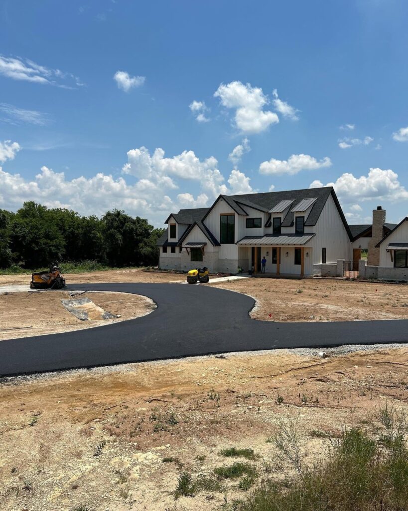Freshly paved driveway leads to a large house