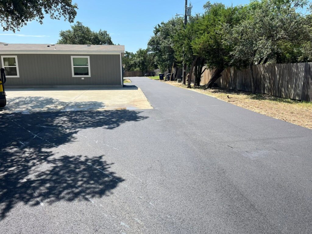 Freshly paved driveway beside a house and trees