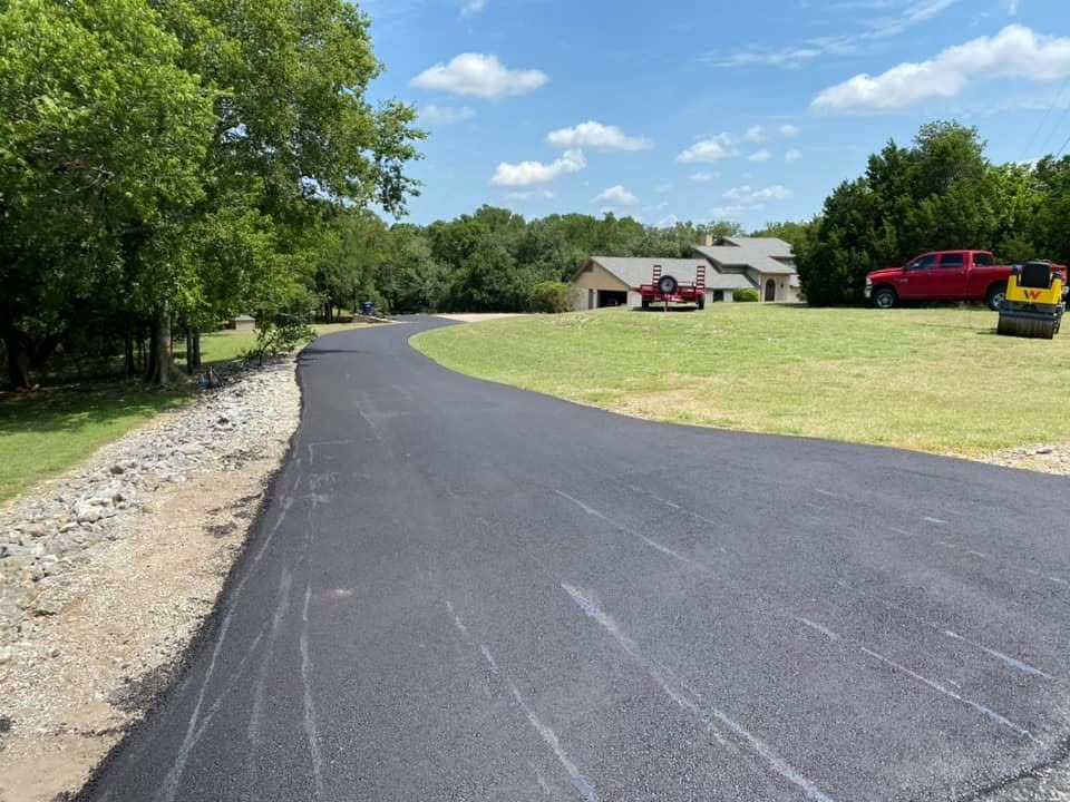 Smooth asphalt driveway curves through a wooded property