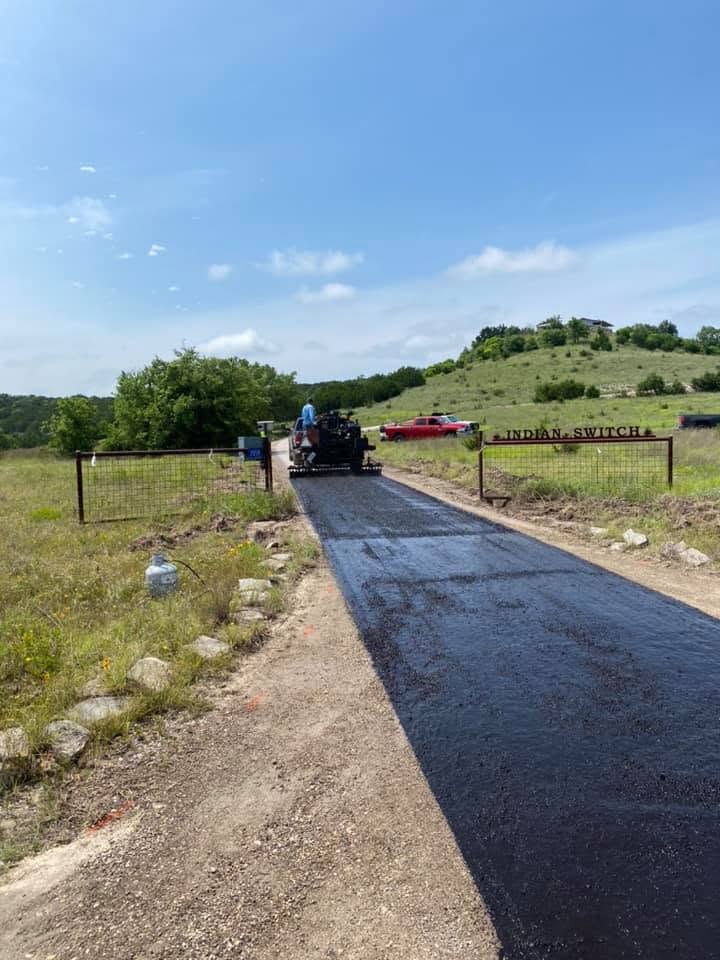 Paving equipment works on a long rural driveway