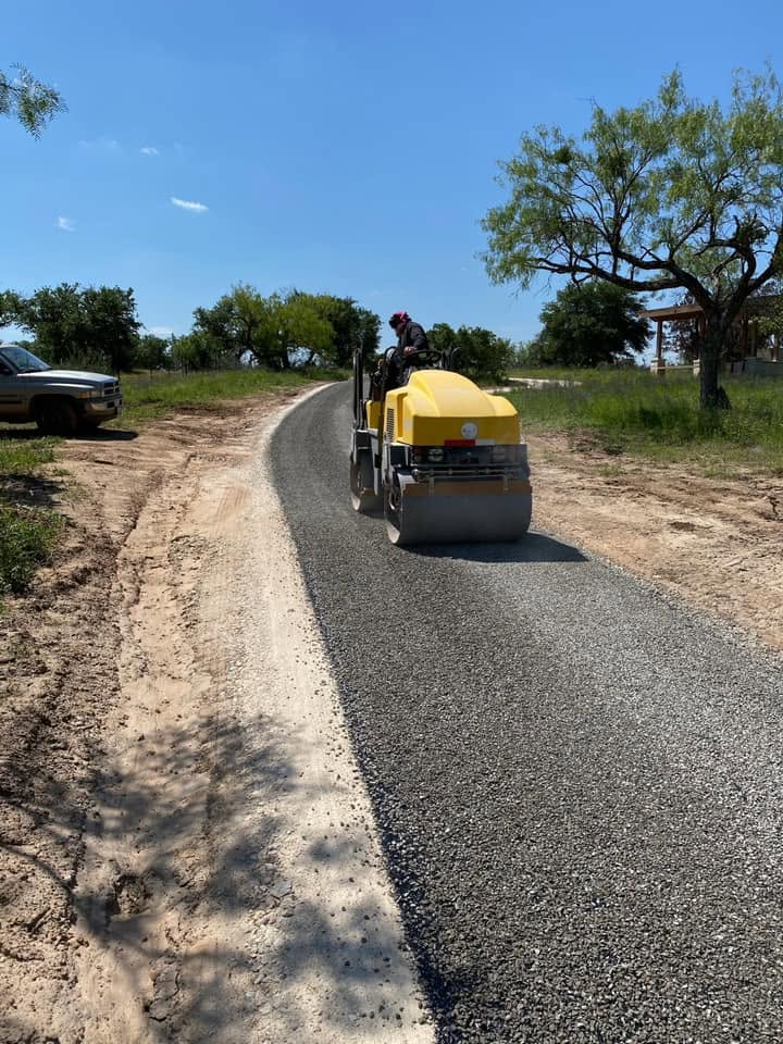 Road roller compacts fresh asphalt on a rural driveway